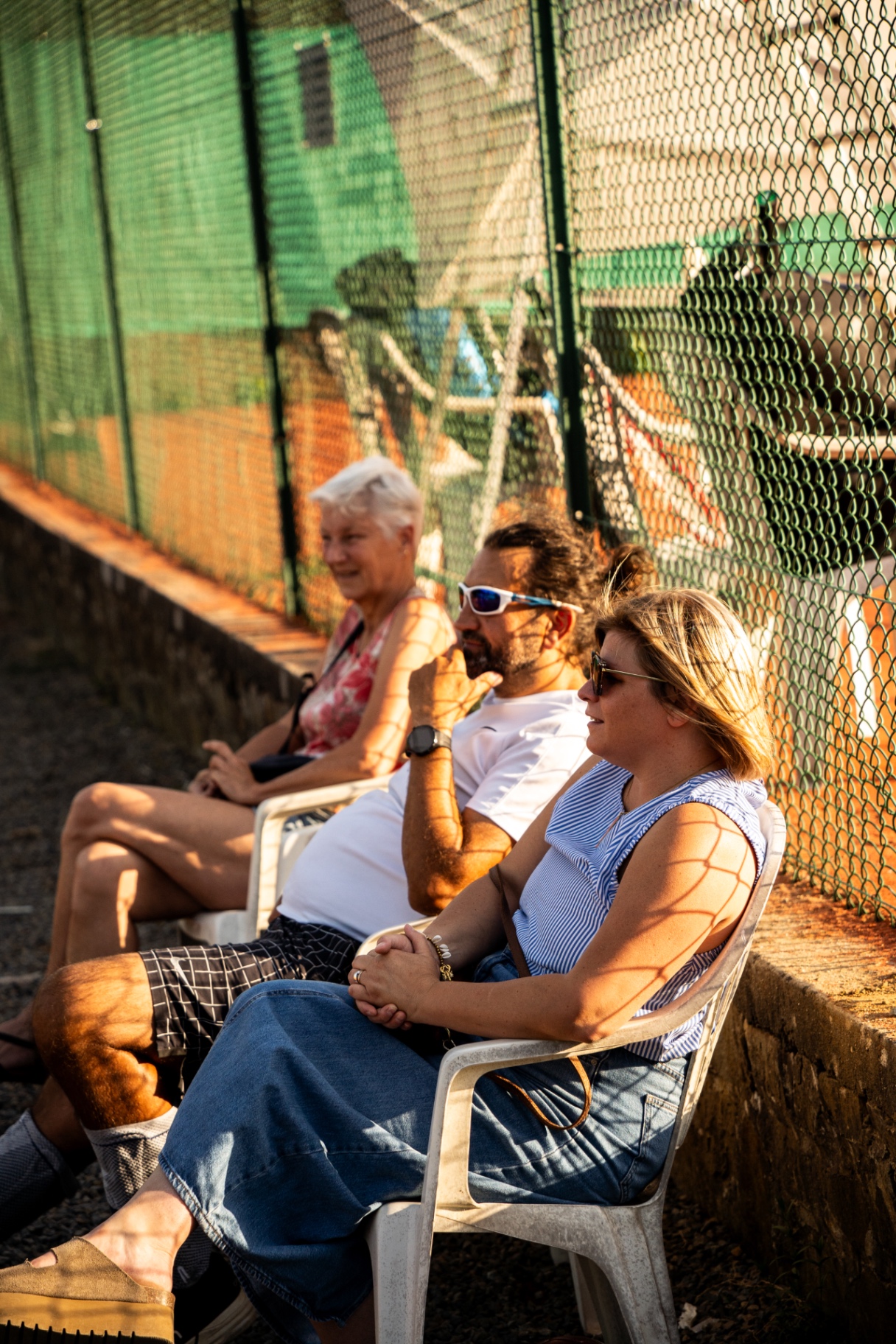 Membres du TCG installés au bord du court pour encourager, au soleil couchant