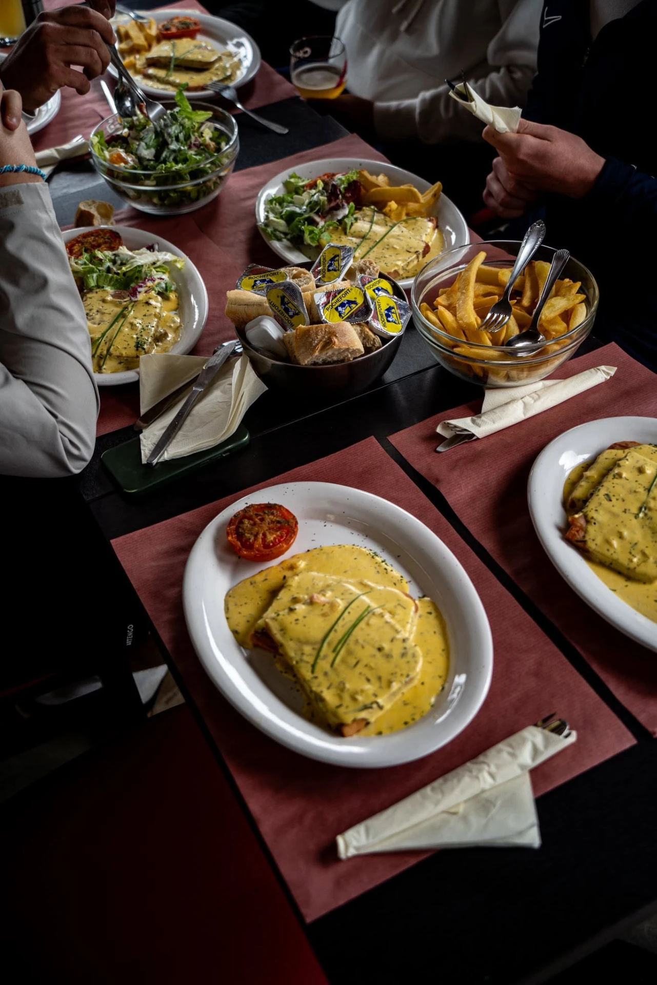 Croque-monsieur, frites et salades sur une table du club-house
