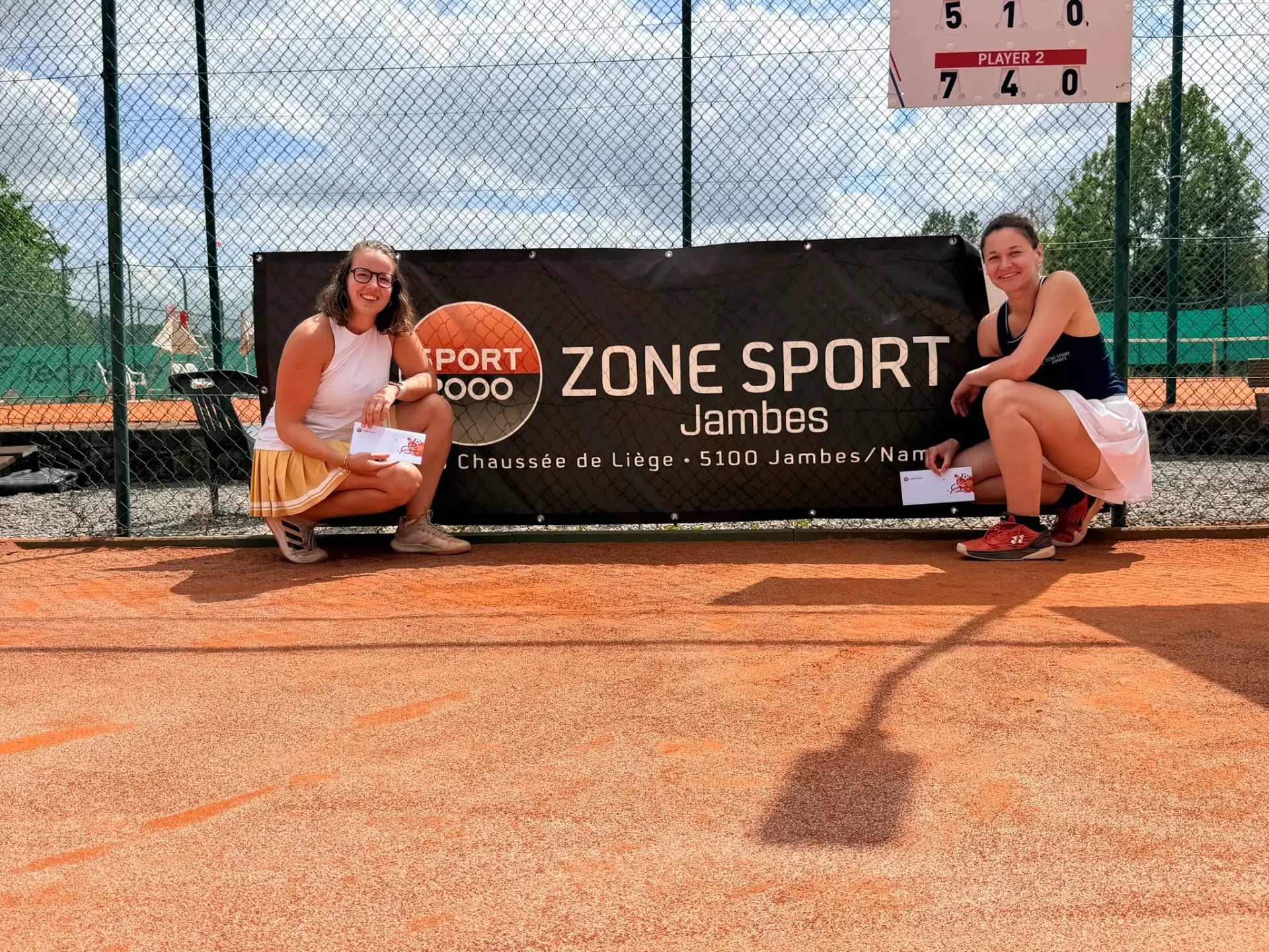 Vainqueure et finaliste dames accroupies devant la bâche Zone Sport Jambes
