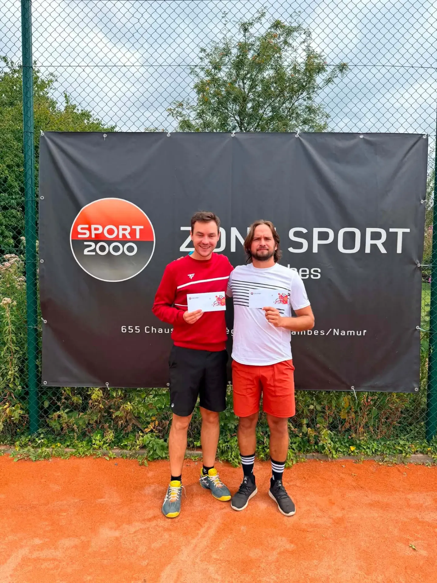 Vainqueur et finaliste messieurs avec leurs chèques devant la bâche Zone Sport