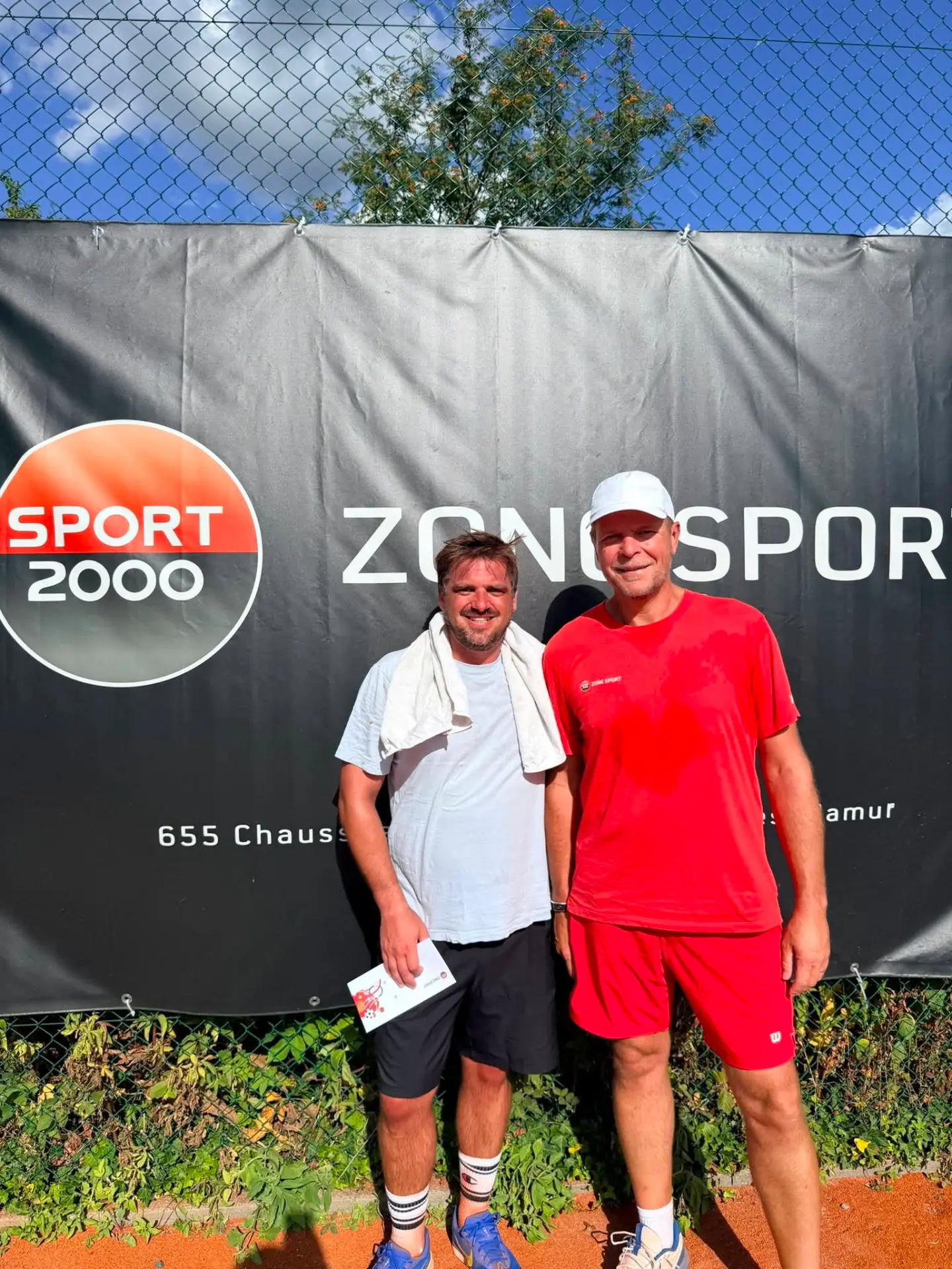 Vainqueur et finaliste messieurs devant la bâche Zone Sport du TC Godinne